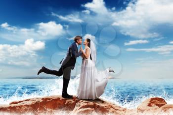 Bride and groom kissing on the sea shore. Romantic honeymoon