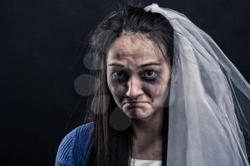 Disheveled bride with tear-stained face on black background. Studio photo shoot
