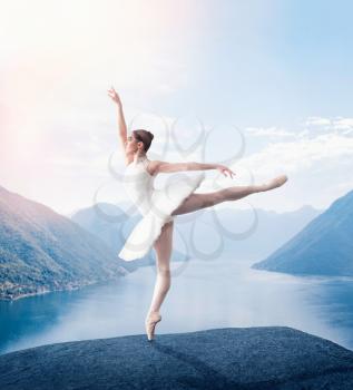 Grace ballerina keep the rack in studio, lake and mountains on background