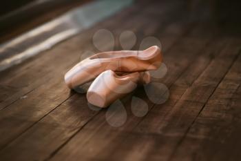 Ballet pointe shoes on the wooden floor closeup. Dance footwear concept 