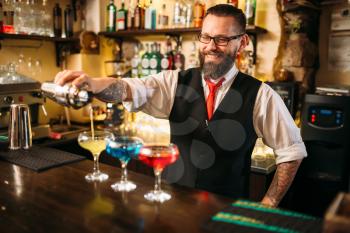 Bartender with shaker making alcohol beverages behind a bar counter in nightclub