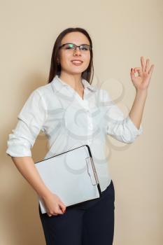 Young female accountant with notebook shoes OK sign