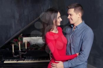 Beautiful young loving couple embraces,retro piano on background