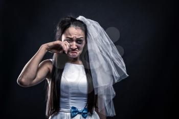 Bride with tearful face, unhappy marriage. Studio photo shoot on black background