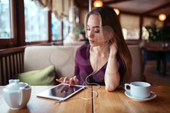 Beautiful woman with tablet pc using internet in restaurant. Girl with modern gadget using 4g in restaurant.