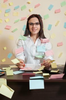 Young female accountant in glasses sitting at workplace, stickers all around