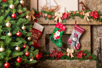 Stone fireplace decorated with christmas stockings. Xmas tree and holiday decoration on background