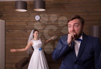 Portrait of smiling bride and surprised groom, wooden background.