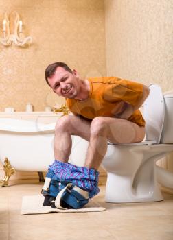 Diarrhea problem concept. Man with pants down sitting on the toilet bowl