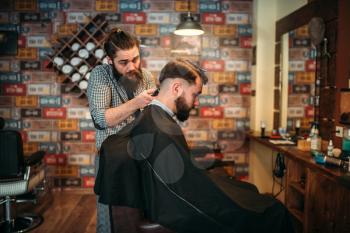 Barber makes hairstyle of the client man by clipper. Barbershop concept