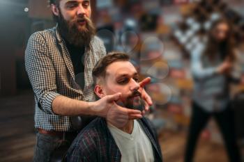Barber shows his work to the client man. Hairdressing salon interior on background