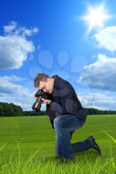 Photographer taking macro picture of the grass on digital camera, green meadow on background