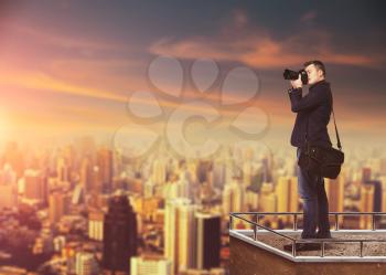 Photographer with digital camera against cityscape on background