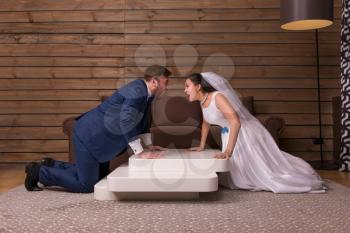 Portrait of swearing bride and groom, newlyweds relationship, wooden room on background.