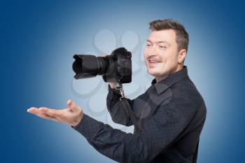 Smiling man with professional digital camera on blue background