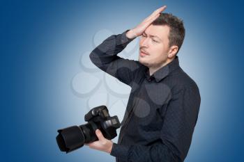 Photographer with professional digital camera in studio on blue background