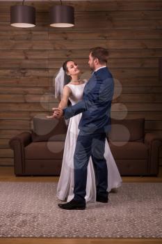 Romantic newlyweds couple dancing wedding dance. Wooden background. Groom and bride