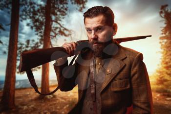 Hunter man in vintage hunting clothing with old gun, forest on background. Hunt lifestyle