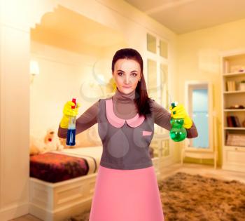 Young housemaid woman in uniform and rubber gloves cleaning the room. Housekeeping concept