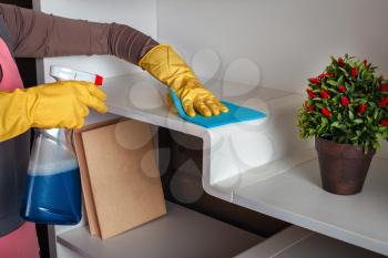 Female hands in rubber gloves cleans the shelf with spray. Cleaning servisce concept