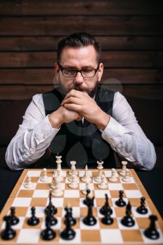 Pensive male chess player in glasses thinking about game strategy. Intelligence competition concept