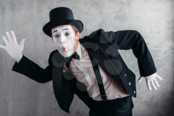 Pantomime theater artist posing, mimic male person with white makeup mask. Comedy actor in suit, gloves and hat