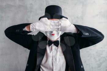Circus artist posing, pantomime with white makeup mask. Comedy actor in suit, gloves and hat