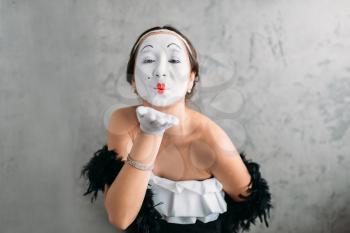 Pantomime theater actress with white makeup mask posing in studio. Comedy female artist performing. April fools day concept