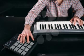 Male audio engineer hands on musical keyboard, closeup. Digital sound recording technology. Media engineering