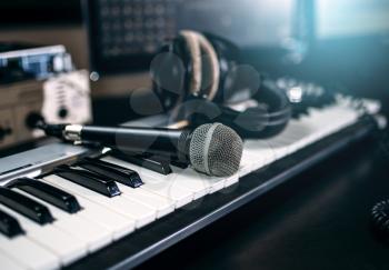 Professional music studio equipment, closeup. Musical keyboard, microphone and headphones. Audio recording tools