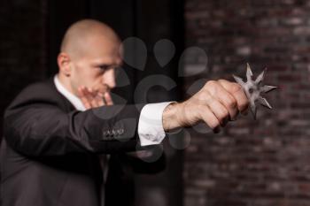 Professional secret agent explore oriental martial arts concept. Bald contract murderer in suit and red tie holds asterisk ninja. Chouraqui dangerous weapon in right hands