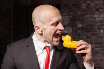 Contract killer in suit and red tie is going tp eat a little toy duck