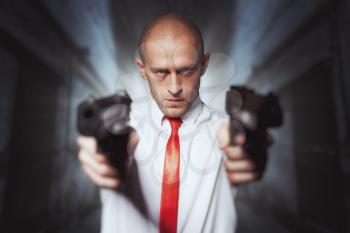 Bald killer in red tie aims with two pistols. Professional secret agent concept. Assassin with guns, wallpaper, background or poster