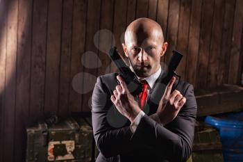 Bald contract killer in suit with two pistols. Professional secret agent concept. Assassin with guns, wallpaper, background or poster