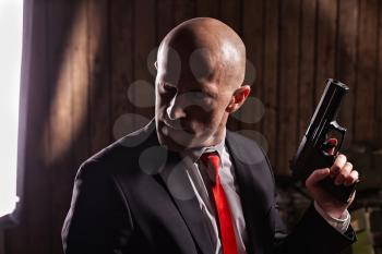 Contract assassin wallpaper, background or poster. in suit and red tie holds gun. Professional secret agent concept. Murderer with pistol, wallpaper, background or poster