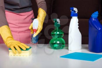 Female person in uniform and rubber gloves cleans the table. Cleaning servisce concept
