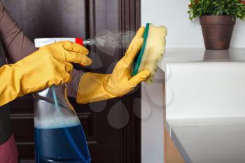 Female hands in rubber gloves cleans the shelf with spray. Cleaning servisce concept
