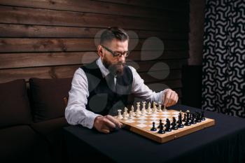 Serious male chess player in glasses makes victory move. Win strategy concept
