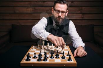 Serious male chess player in glasses makes victory move. Win strategy concept