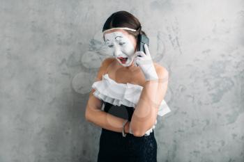 Mime actress performing with mobile phone. Comedy female artist posing. Comedian with white makeup mask on face