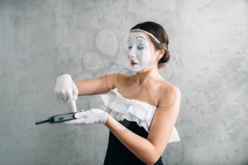 Mime female artist performing with mobile phone. Woman circus clown. Pantomime theater comedian with white makeup mask on face