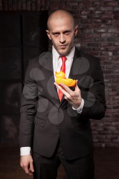 Contract killer in suit and red tie shows his fears and secrets. Special agent holds little toy duck in hand. Hired murderer wallpaper or background