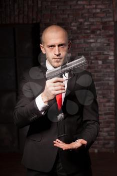 Contract murderer wallpaper, background or poster concept. Assassin in suit and red tie changes the clip into the gun
