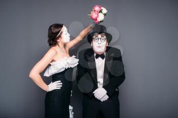 Comedy actor and actress posing with flower bouquet. Mime theater performers posing. Pantomime artists