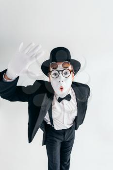Comedy mime artist in glasses and white makeup mask. Pantomime in suit, gloves and hat. April fools day concept