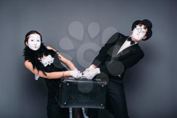 Mime actor and actress performing with suitcase. Pantomime theater performers with bag
