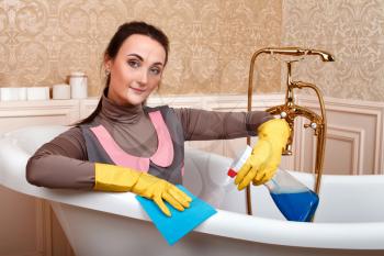 Female worker in cleaning servisce uniform sitting in bath. Housekeeping concept