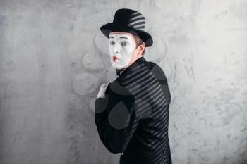 Male comedy artist posing, pantomime with white makeup mask. Circus actor in suit, gloves and hat