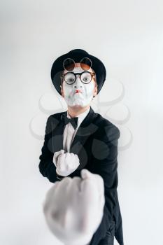Comedy mime artist in glasses and white makeup mask. Pantomime in suit, gloves and hat. April fools day concept