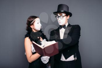 Two pantomime theater performers posing with book. Mime actor and actress performing